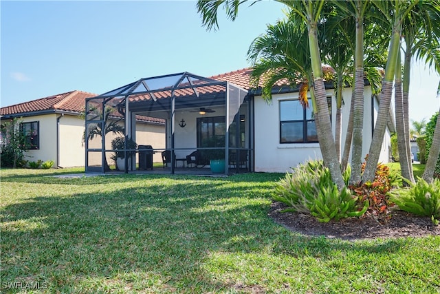 back of property with a lawn and glass enclosure