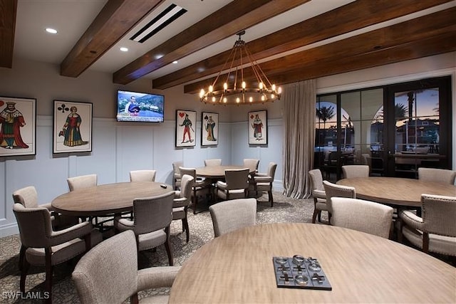 dining room with a notable chandelier, beam ceiling, and carpet