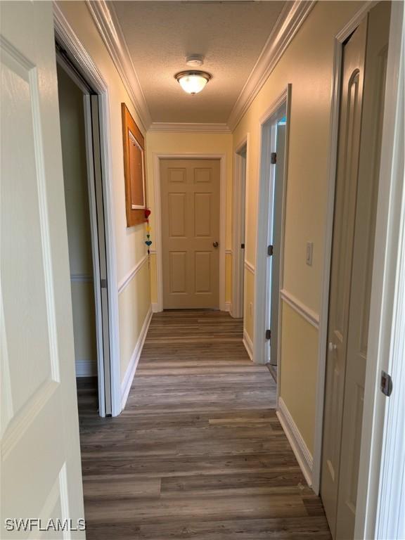 corridor with baseboards, dark wood-type flooring, and crown molding