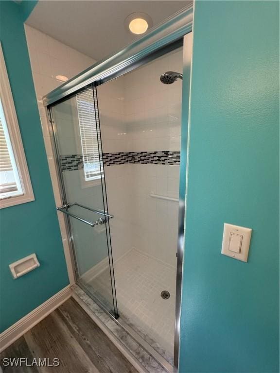 full bathroom featuring a stall shower, wood finished floors, and baseboards