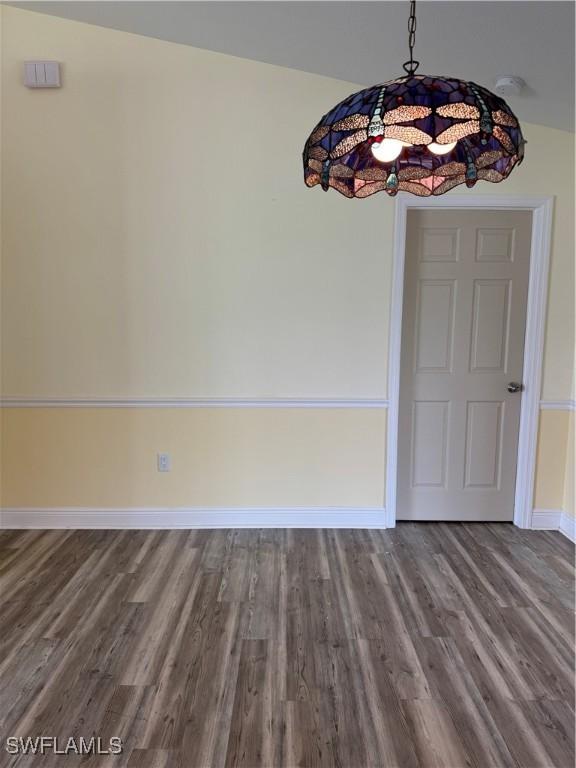 unfurnished dining area with wood finished floors and baseboards