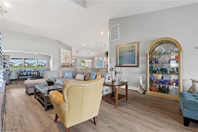 living room featuring high vaulted ceiling and light hardwood / wood-style floors