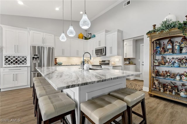 kitchen featuring stainless steel appliances, white cabinetry, sink, and a center island with sink