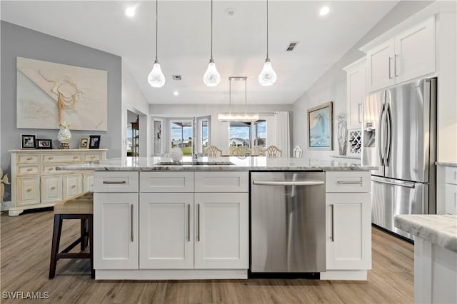 kitchen featuring stainless steel appliances, white cabinetry, and decorative light fixtures