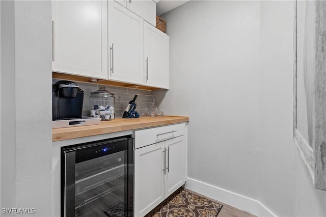 bar featuring wood counters, white cabinets, beverage cooler, decorative backsplash, and hardwood / wood-style flooring