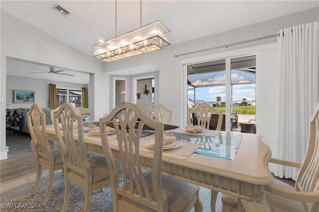 dining room with ceiling fan with notable chandelier, vaulted ceiling, and wood-type flooring