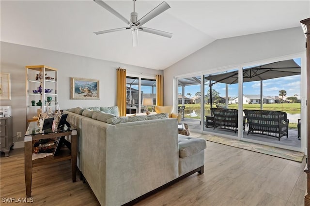 living room featuring a water view, ceiling fan, vaulted ceiling, and light hardwood / wood-style flooring