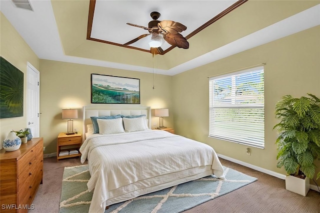 bedroom with light carpet, ceiling fan, and a tray ceiling