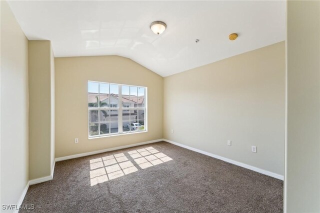 unfurnished room with lofted ceiling and dark carpet