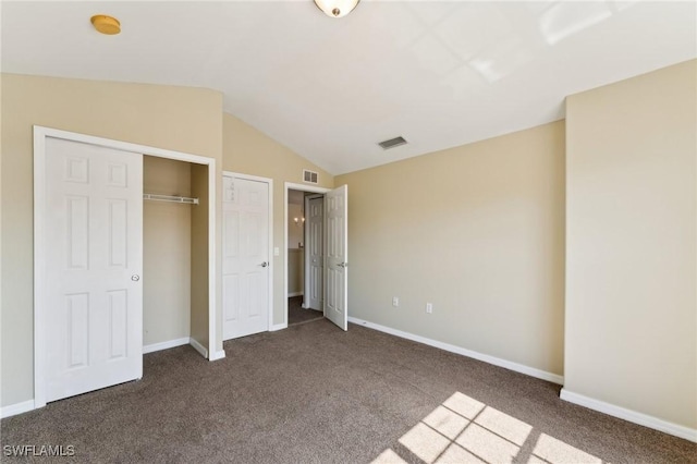 unfurnished bedroom featuring dark carpet, vaulted ceiling, and a closet