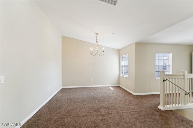 carpeted empty room with a notable chandelier and vaulted ceiling