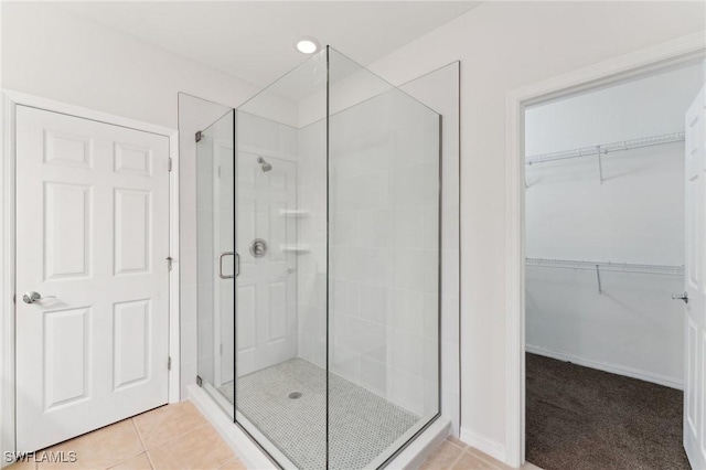 bathroom with a shower with door and tile patterned floors