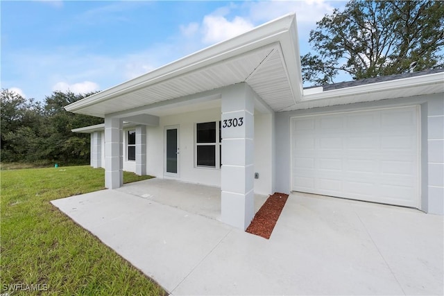 view of front of home with a garage, stucco siding, driveway, and a yard