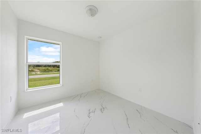 spare room with marble finish floor and baseboards