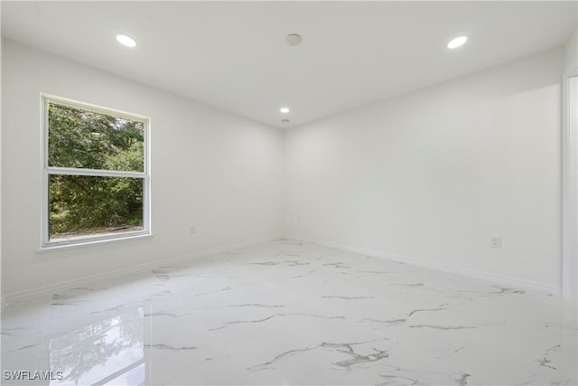 empty room featuring baseboards, marble finish floor, and recessed lighting