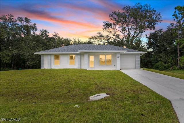 view of front of house featuring a garage, driveway, roof with shingles, and a front yard