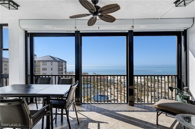 sunroom featuring a water view and ceiling fan