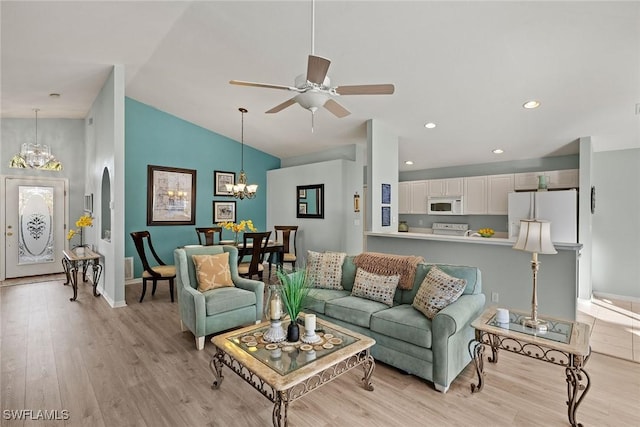 living room with lofted ceiling, ceiling fan with notable chandelier, and light hardwood / wood-style floors