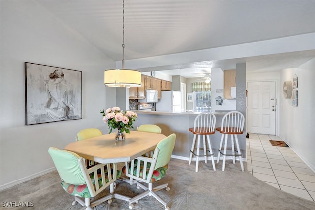 dining space with vaulted ceiling and light colored carpet