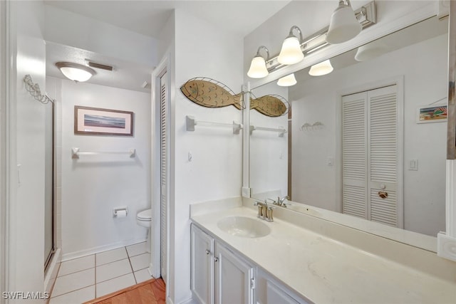 bathroom featuring vanity, a shower with shower door, tile patterned floors, and toilet