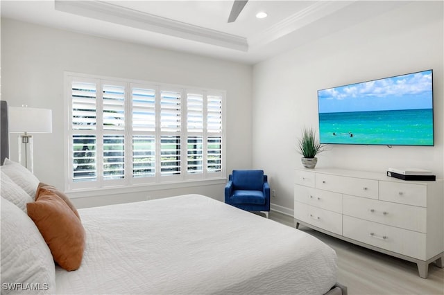 bedroom featuring ceiling fan, ornamental molding, a tray ceiling, and light hardwood / wood-style floors