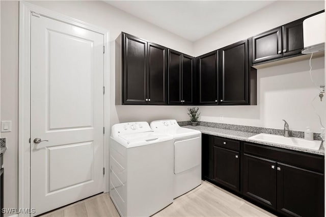 washroom with washer and dryer, sink, cabinets, and light wood-type flooring