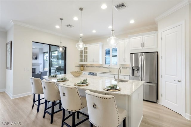 kitchen featuring pendant lighting, sink, light stone counters, white cabinets, and stainless steel fridge with ice dispenser