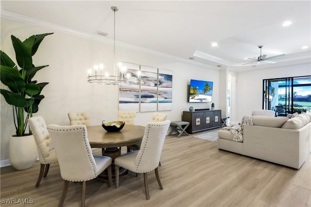 dining room featuring crown molding, ceiling fan with notable chandelier, light hardwood / wood-style floors, and a raised ceiling