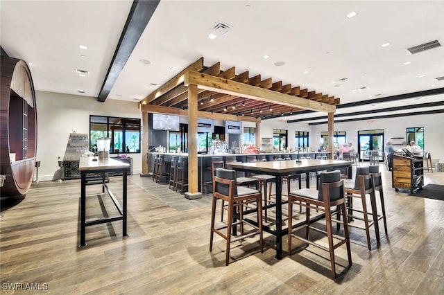 dining space with light hardwood / wood-style flooring and beamed ceiling