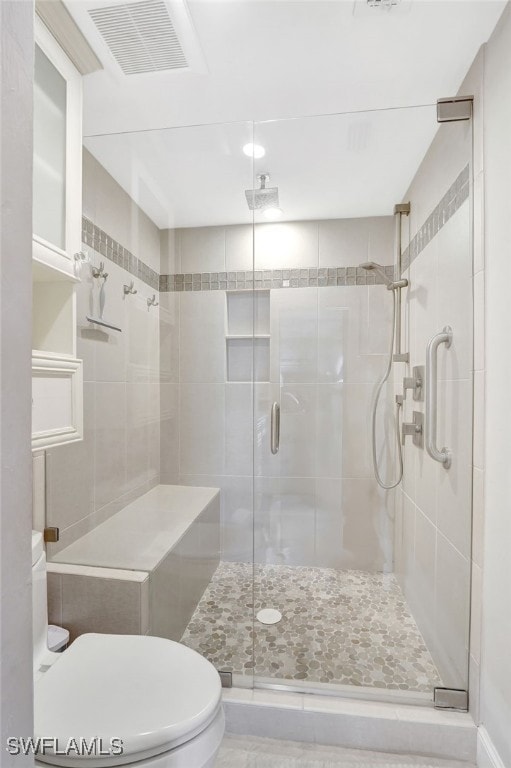 bathroom with a shower with door and toilet