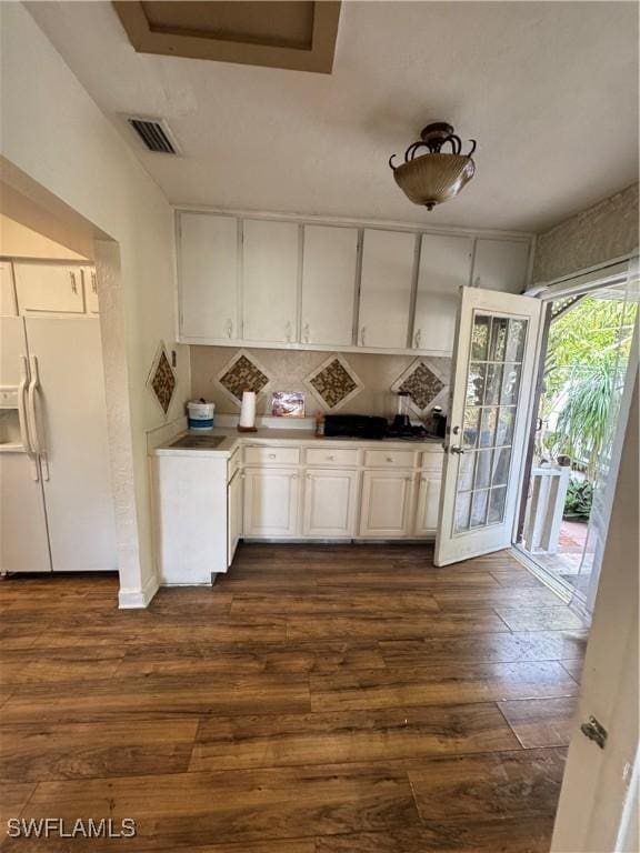 kitchen featuring dark hardwood / wood-style flooring, white refrigerator with ice dispenser, decorative backsplash, and white cabinets