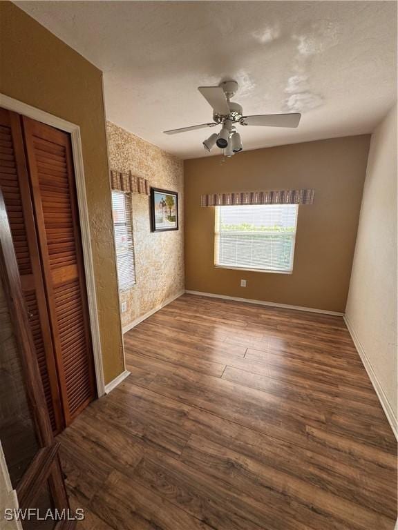 empty room with ceiling fan and dark hardwood / wood-style flooring