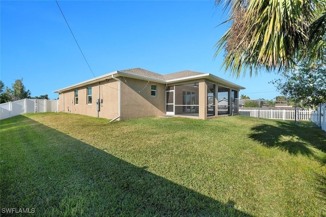 rear view of house with a yard and a sunroom