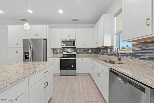 kitchen with sink, white cabinetry, hanging light fixtures, appliances with stainless steel finishes, and backsplash