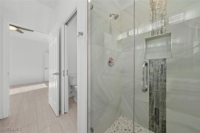 bathroom featuring a shower with door, ceiling fan, and toilet