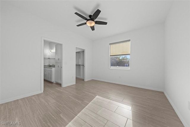 unfurnished bedroom featuring ceiling fan, ensuite bathroom, light hardwood / wood-style floors, a spacious closet, and a closet