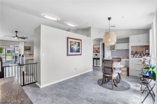 kitchen featuring lofted ceiling, white cabinetry, pendant lighting, ceiling fan, and decorative backsplash