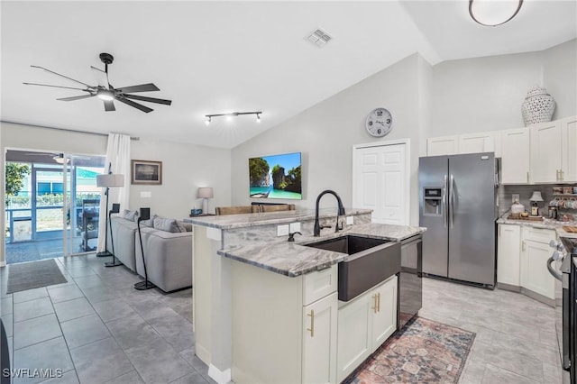 kitchen with sink, light stone counters, stainless steel appliances, a kitchen island with sink, and white cabinets