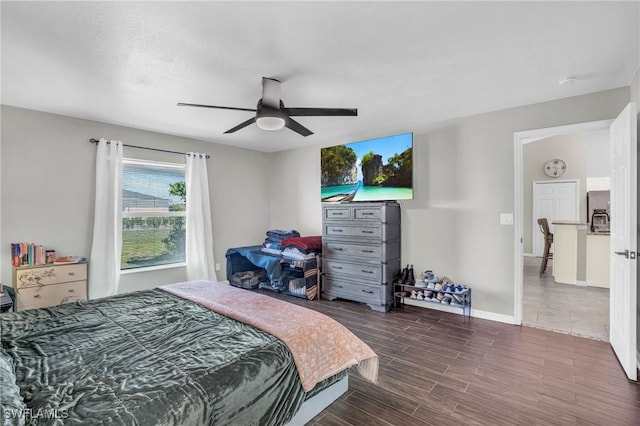 bedroom with dark hardwood / wood-style flooring, ceiling fan, and stainless steel refrigerator with ice dispenser