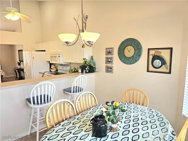 dining area with ceiling fan and a high ceiling