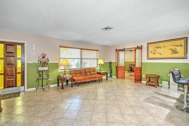 sitting room with a barn door, a textured ceiling, and light tile patterned floors