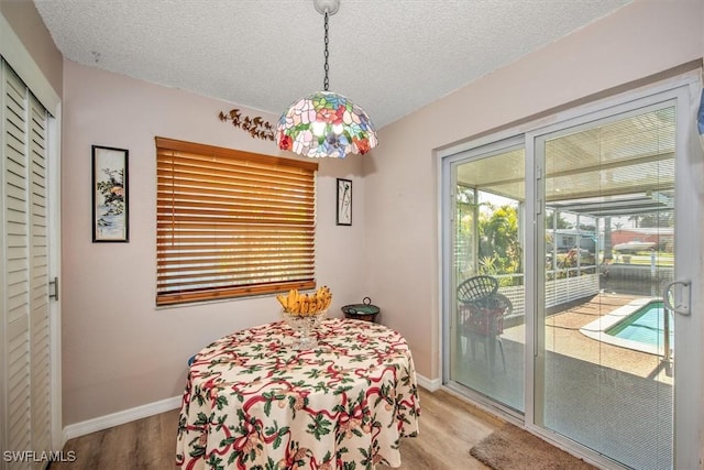 dining area with wood-type flooring and a textured ceiling