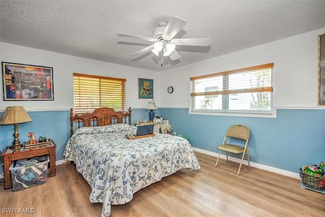 bedroom with ceiling fan, hardwood / wood-style floors, and a textured ceiling