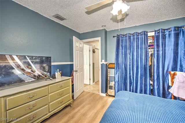 bedroom with ceiling fan, a textured ceiling, and light wood-type flooring