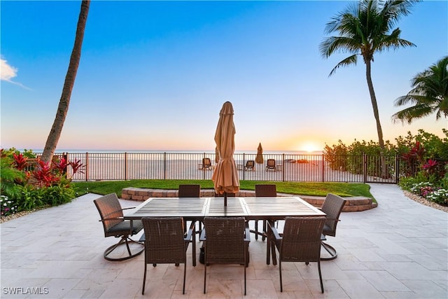 patio terrace at dusk featuring a water view