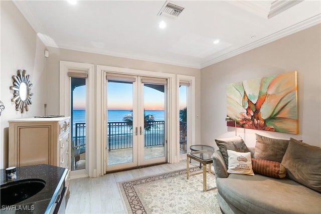 living room featuring sink, crown molding, a water view, light wood-type flooring, and french doors