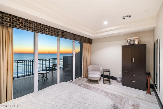 bedroom featuring a water view, access to exterior, and light hardwood / wood-style floors