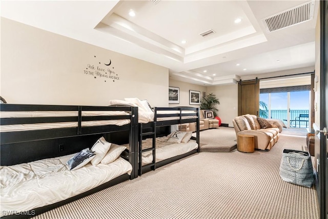 bedroom with access to exterior, a tray ceiling, a barn door, and carpet