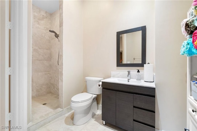 bathroom with tiled shower, vanity, toilet, and tile patterned floors