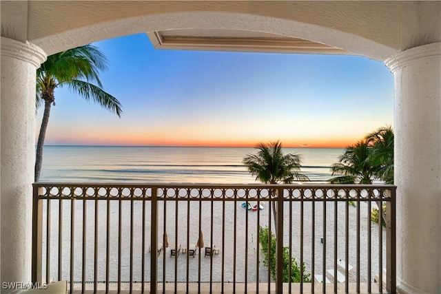 balcony at dusk featuring a water view